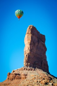 A colorful hot air balloon floats about a red rock butte in Valley of the Gods, Utah